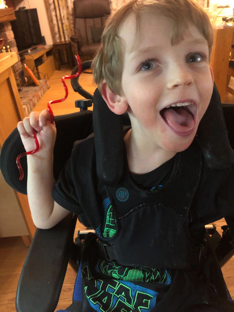 Close up of Quinns' tired but happy face. He holds a red curly straw up in his right hand.