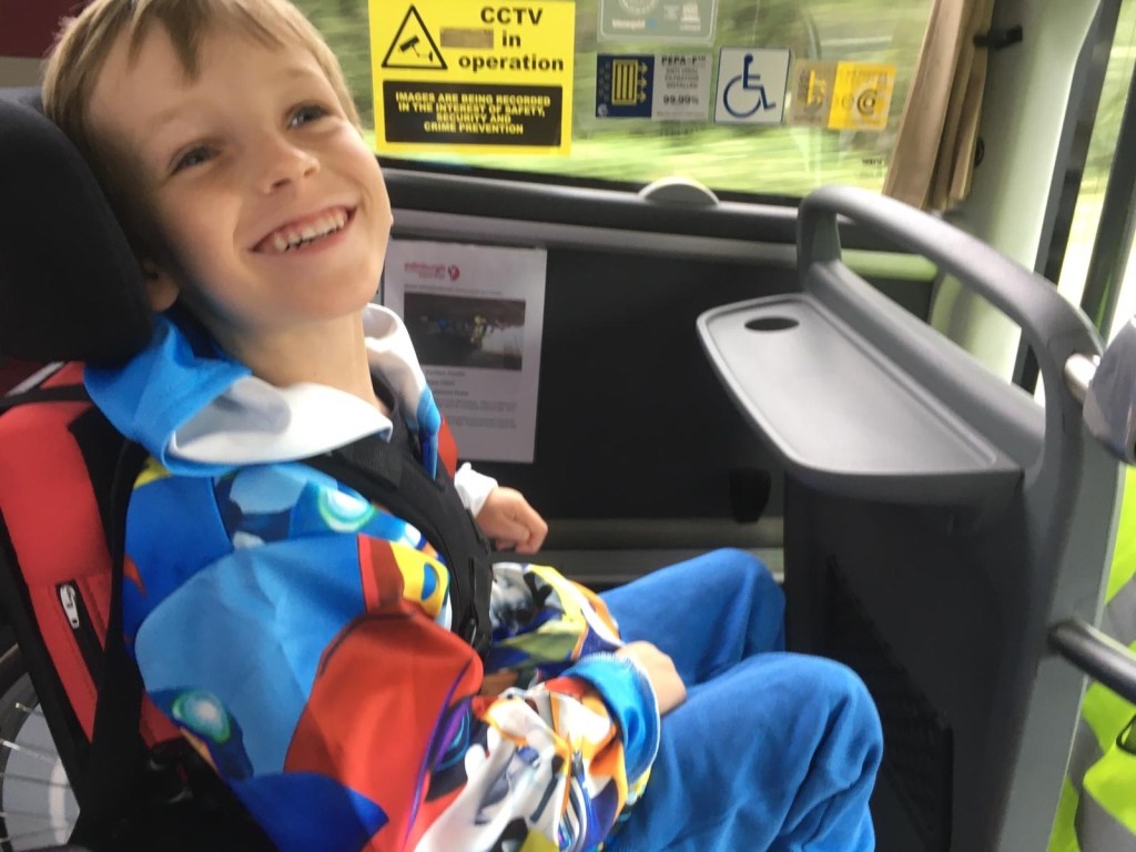 Quinns smiling as he sits in his wheelchair at the front of the coach