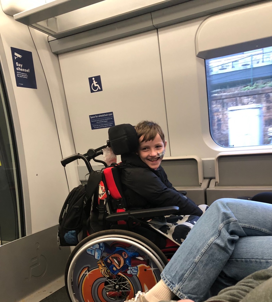 Quinns smiles from the wheelchair space on a train.