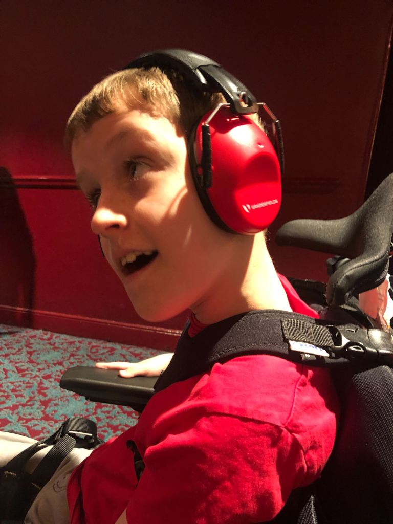 Close up of Quinns wearing his ear defenders ready for the Horrible Histories performance to begin.