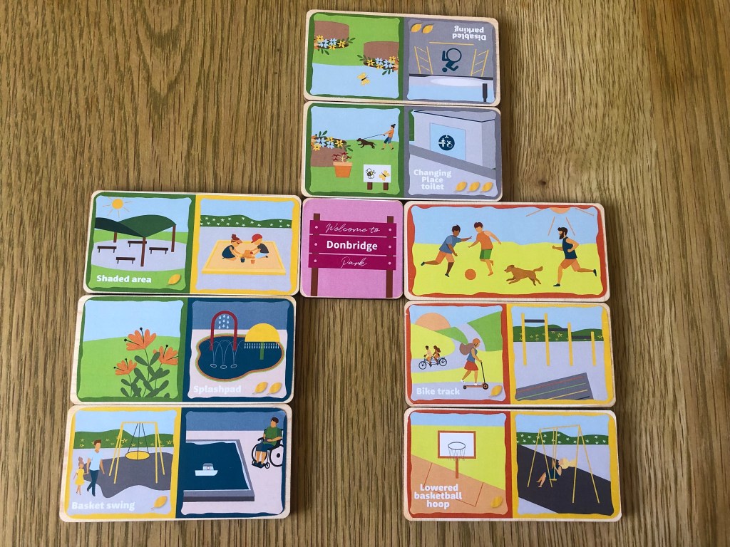 Domino Park dominoes laid out in a game to create the 'Donbridge' park. Point winning dominoes include a Lowered Basketball Hoop, Changing Place Toilet, Bike Track and Disabled Parking.