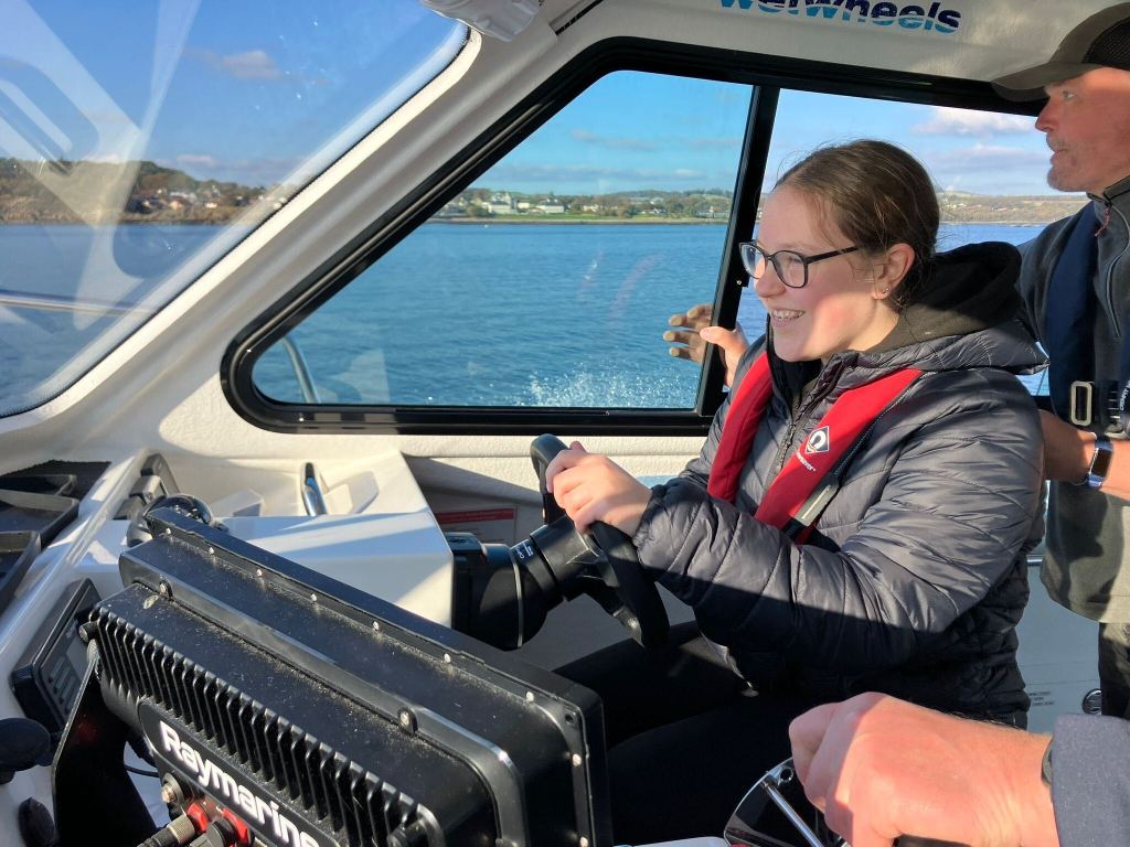 Big Sister smiles with concentration as she steers the Wet Wheels Boat.