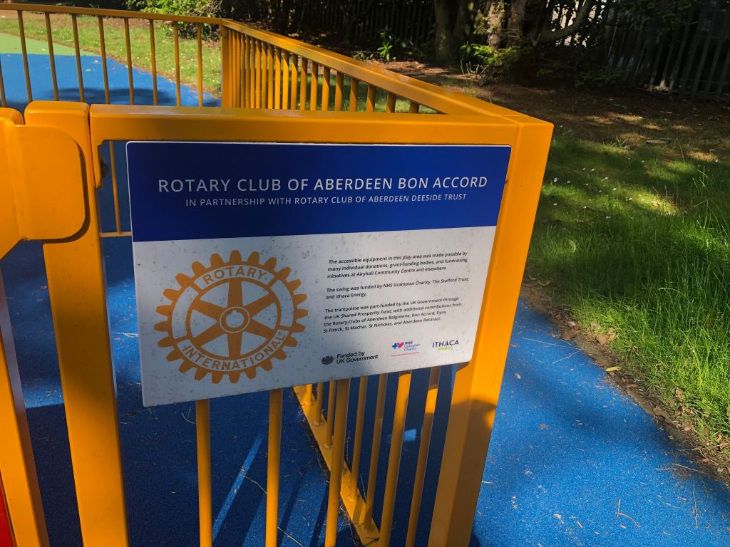 Sign from the Rotary Club of Aberdeen Bon Accord on the side of a wheelchair accessible swing in a Duthie Park.