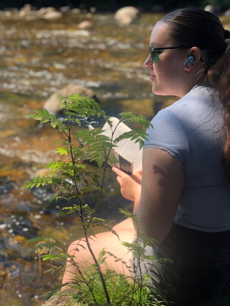 Anita reading her book by the River Dee.